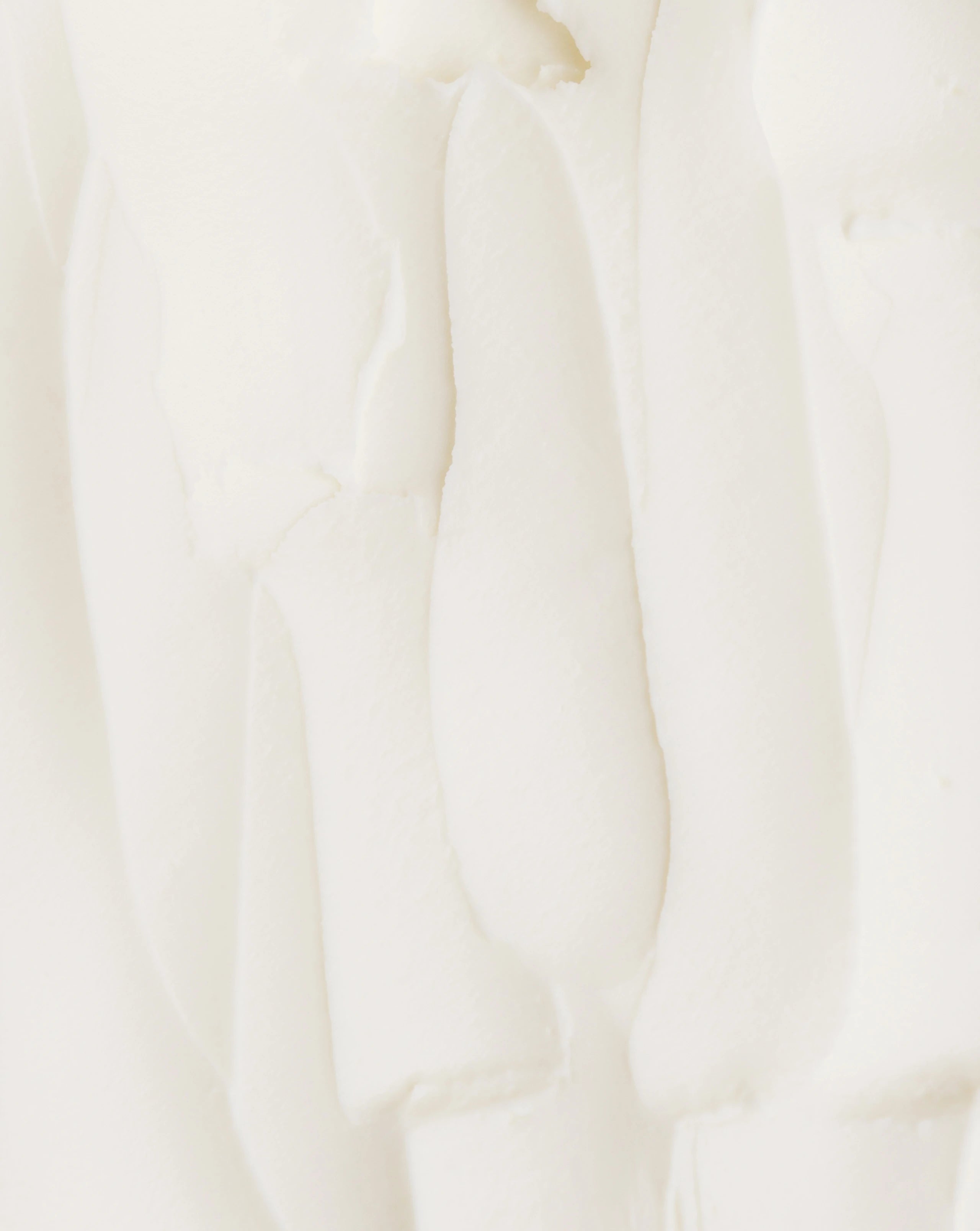 Thick white body lotion texture with smooth swirl, close-up