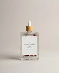 Rose body oil glass bottle with white dropper and wooden cap, label reads Natalic Organics Rose