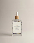 White Lotus body oil bottle with clear glass, dropper pump, and floral label