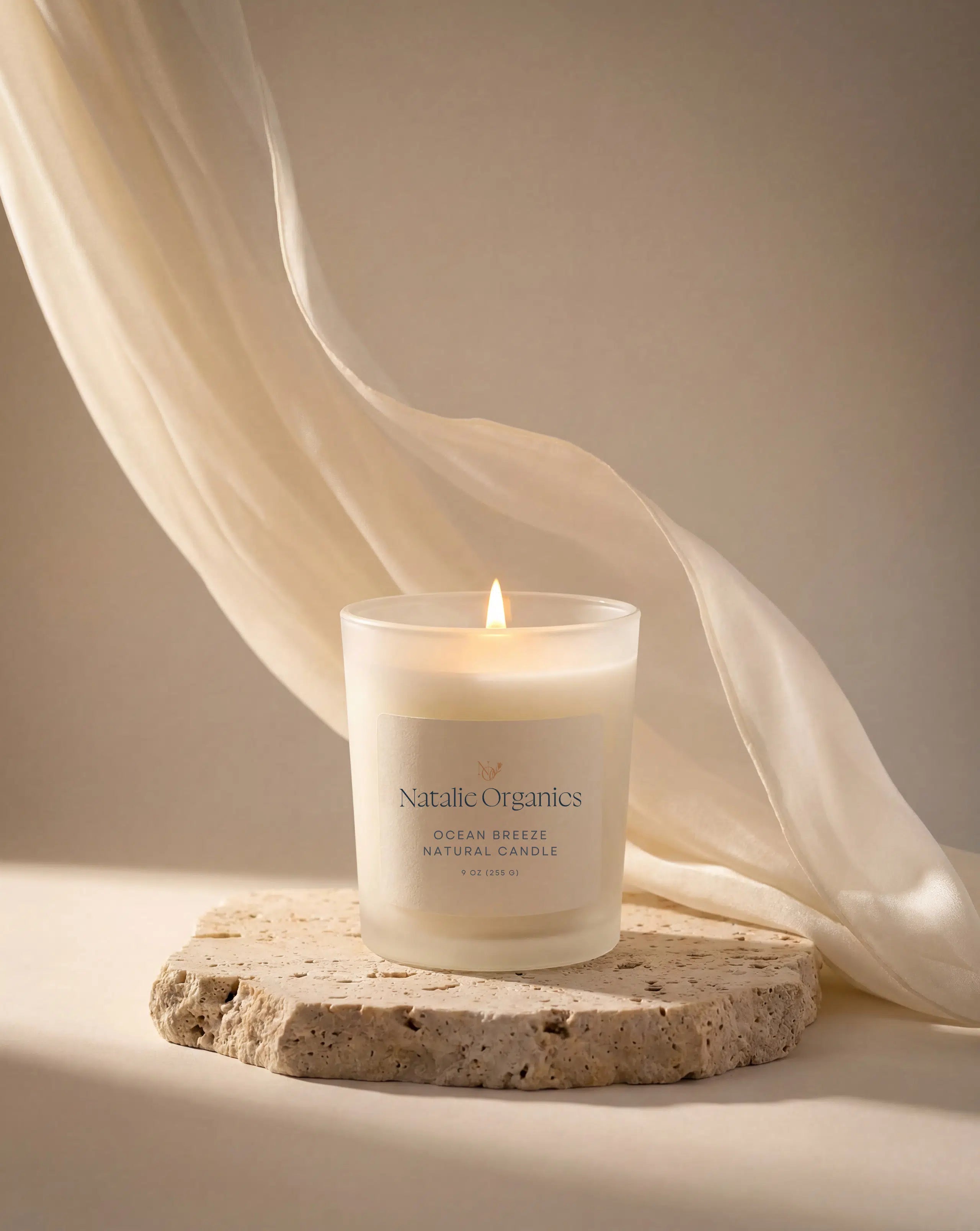 Natalie Organics ocean breeze scented candle in clear glass jar on stone, lit wick