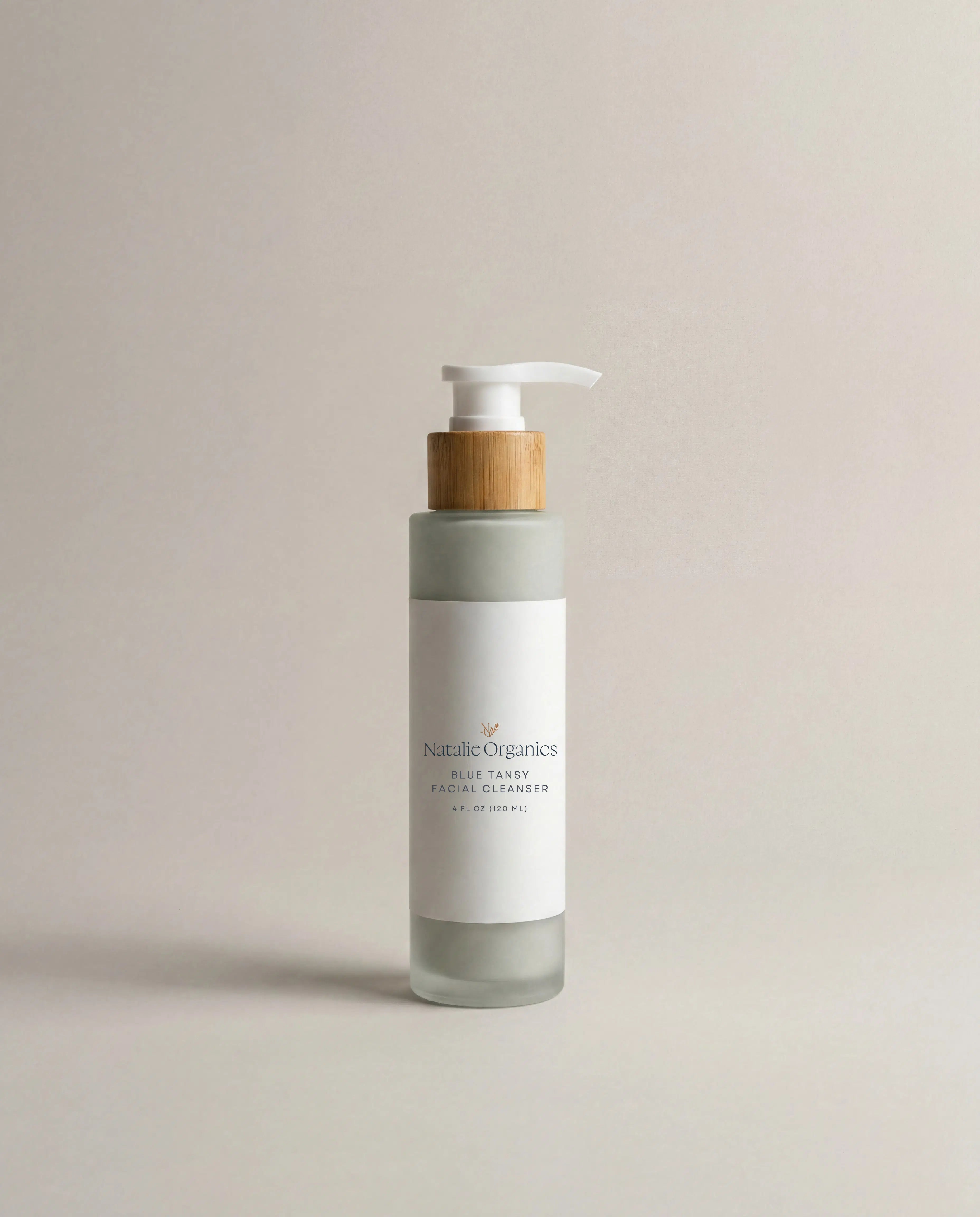 Facial cleanser pump bottle in white and gray with wood-toned dispenser