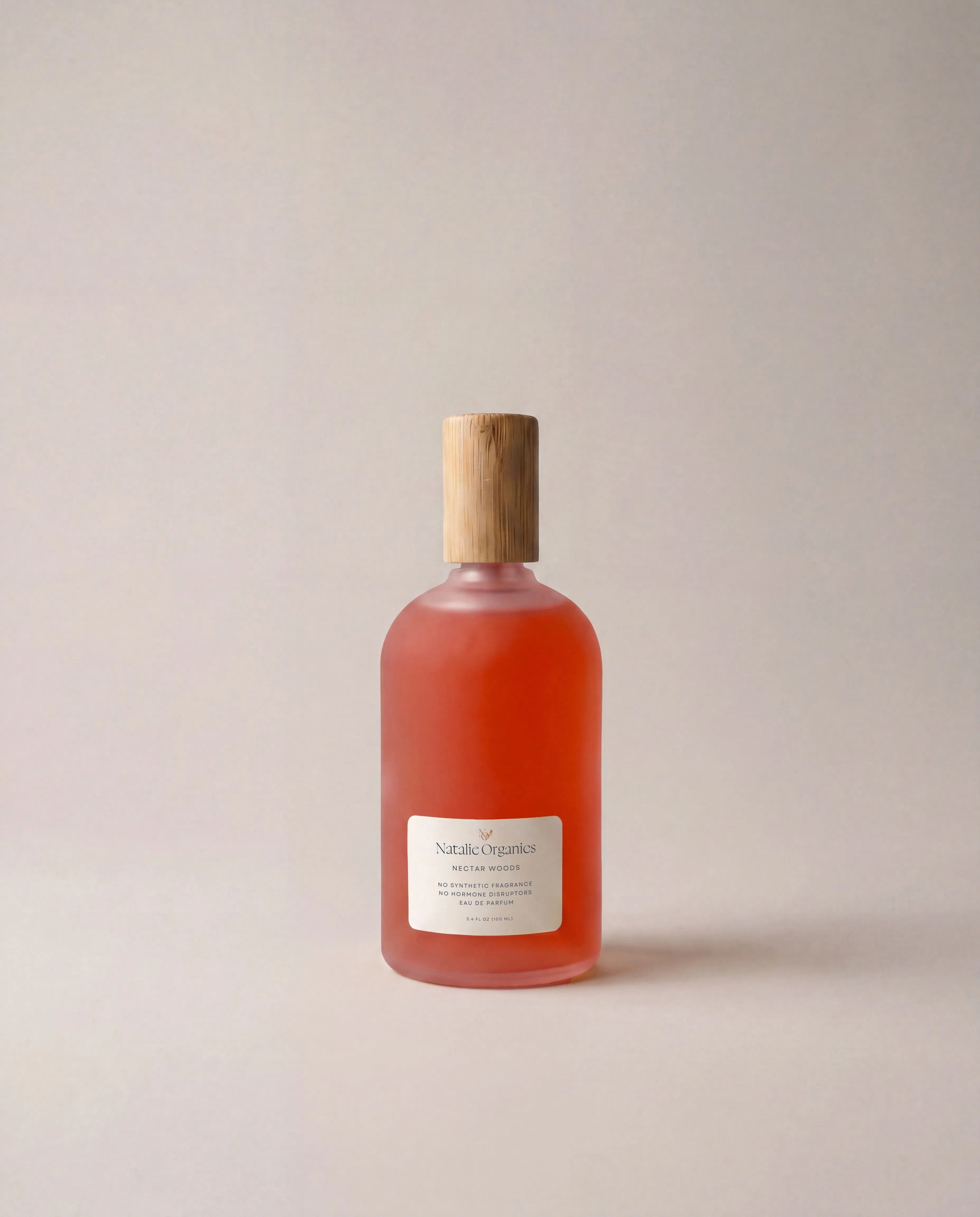 Orange glass fragrance bottle with wooden cap and white label at front