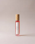 Red glass fragrance bottle with wooden cap and white side label
