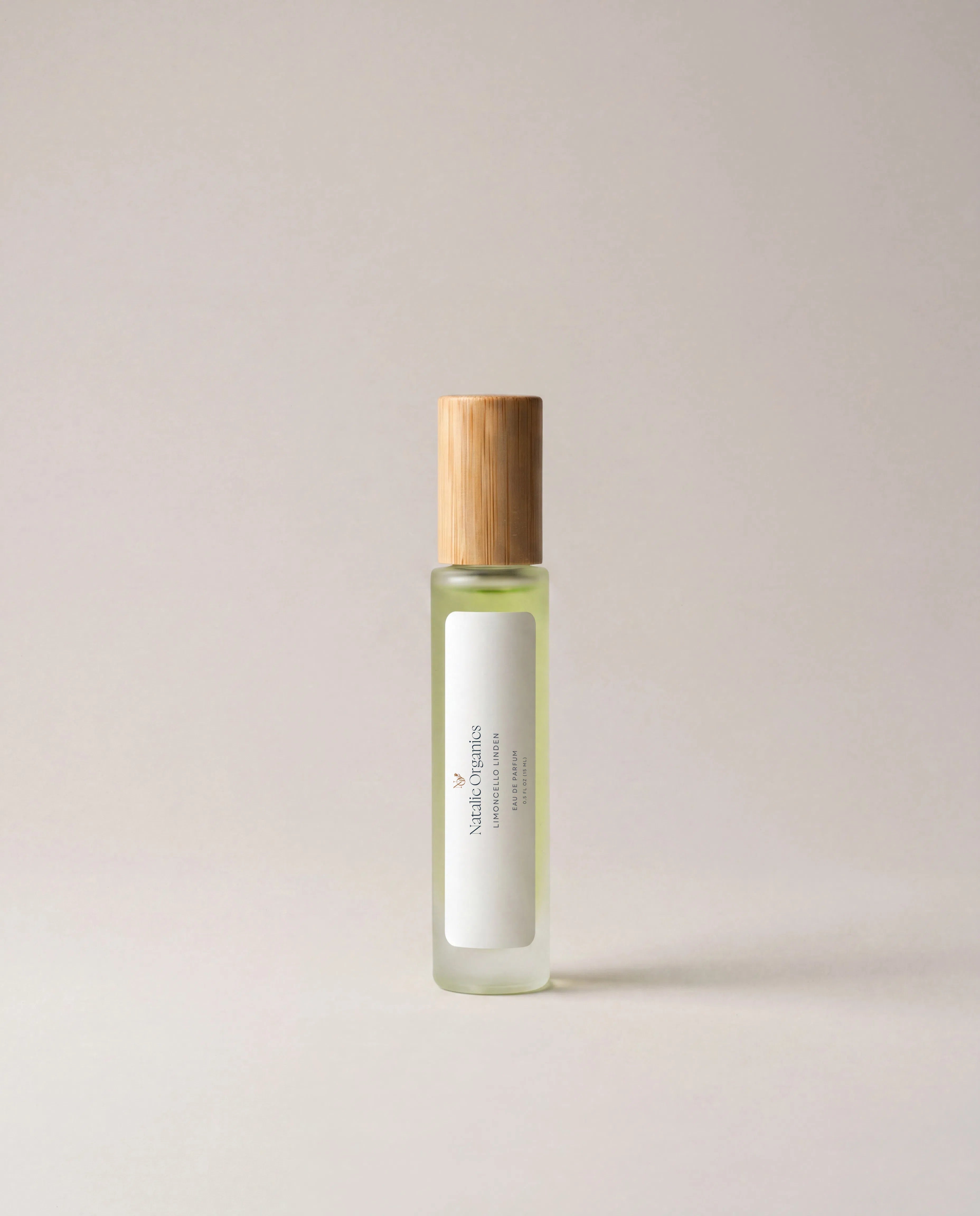Light green fragrance bottle with wooden cap and slim front label.