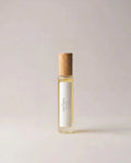 Clear glass fragrance bottle with light wooden cap and cream-colored label