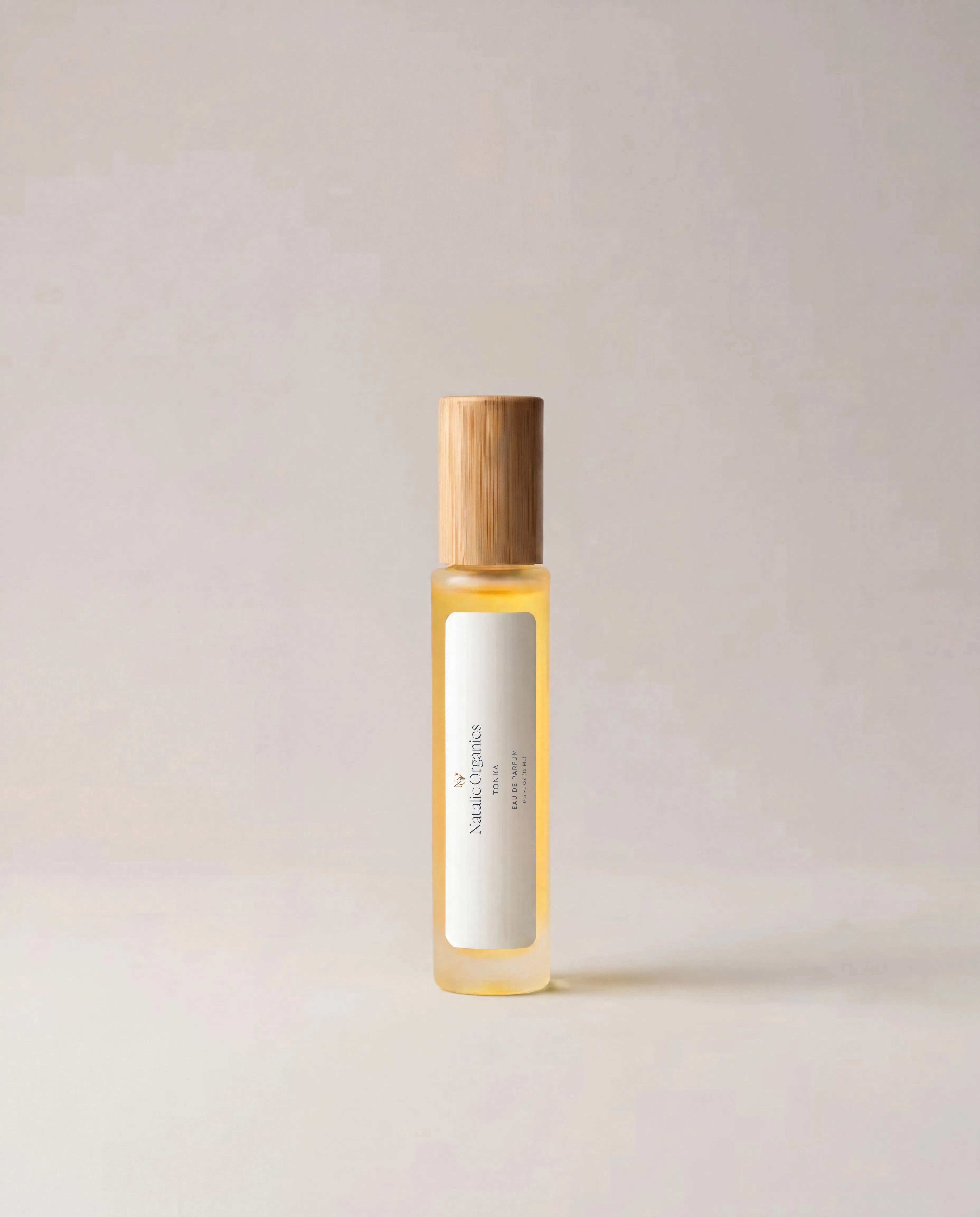 Fragrance bottle with wooden cap, yellow-tinted liquid and white label