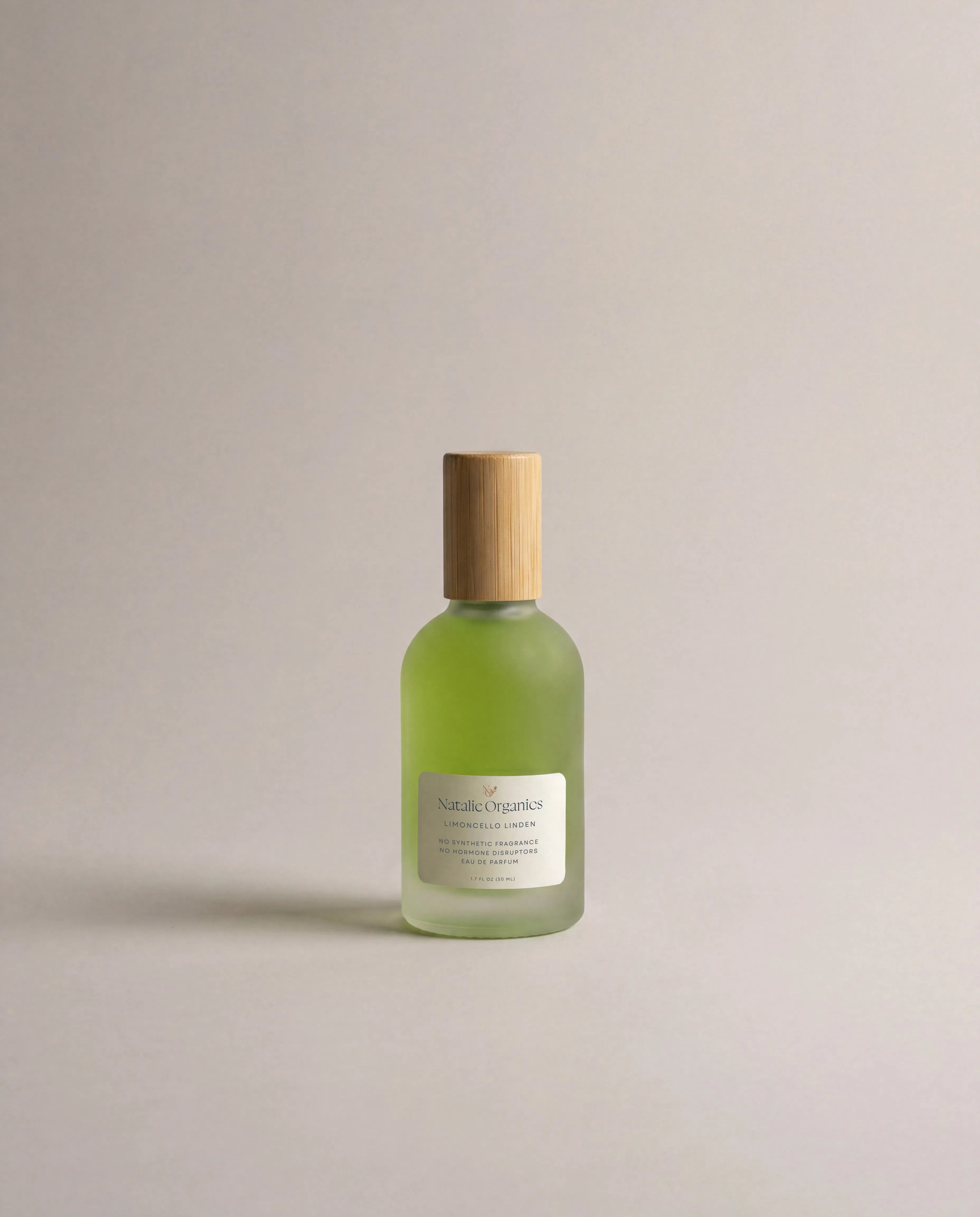 Small green glass fragrance bottle with wooden cap and centered label.