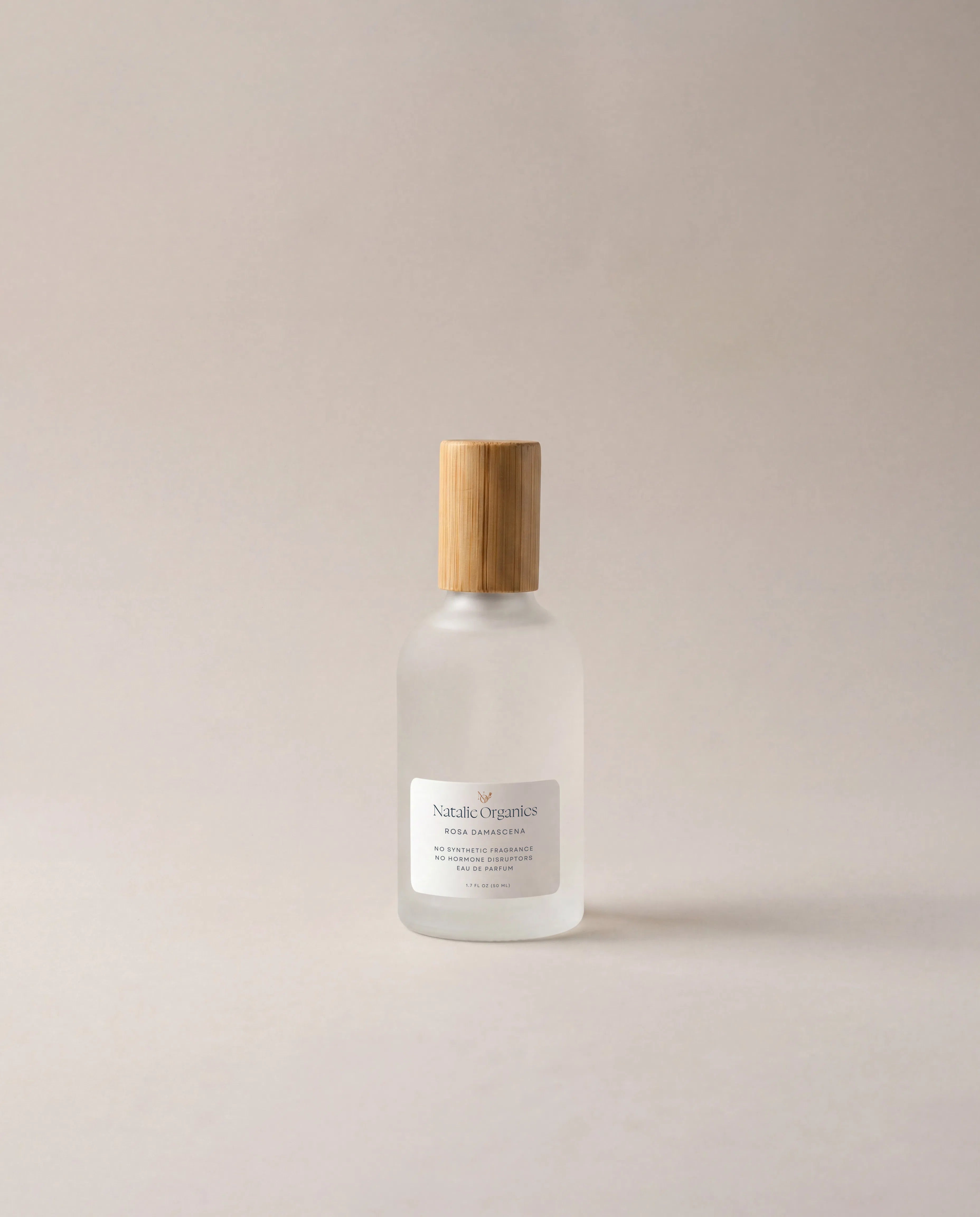 Glass fragrance bottle with rounded shoulders, wooden cap, and front label