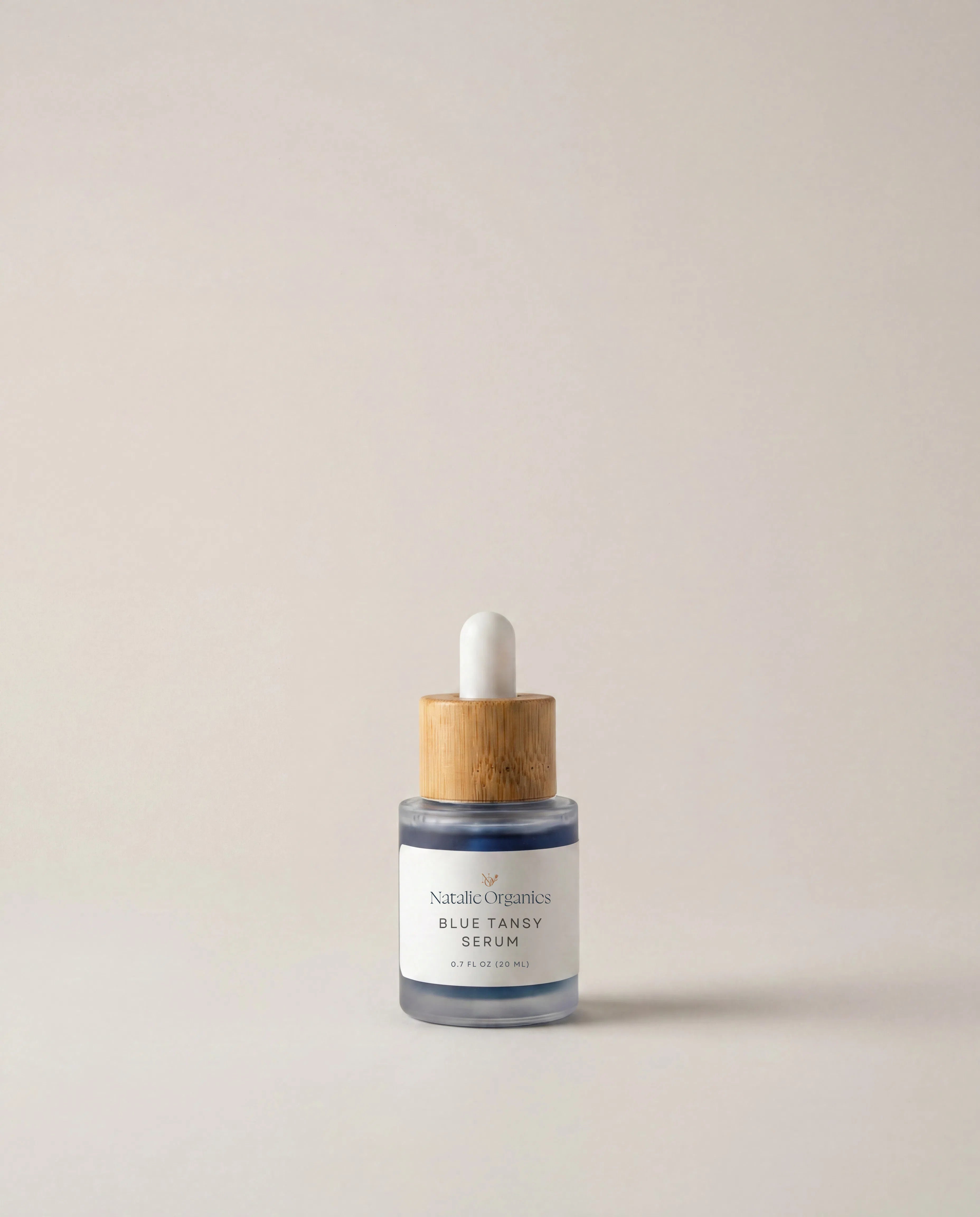 Blue tansy serum bottle with white dropper, glass vial and wood collar